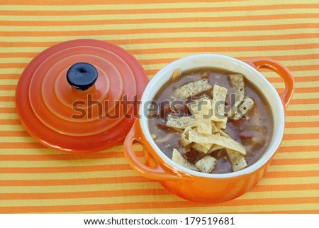 Chicken Tortilla Soup in orange bowl on orange and yellow striped background.