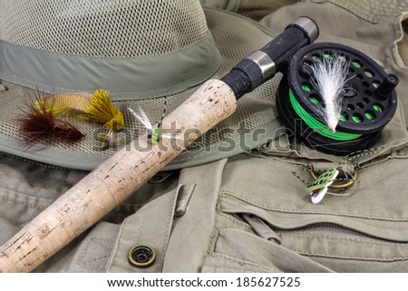 Fly Rod and reel with lures against fishing vest and hat.