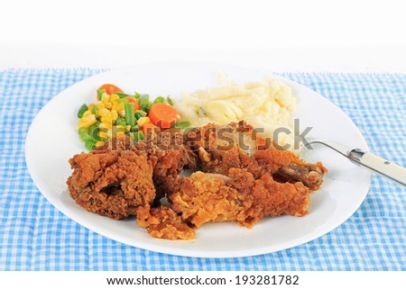 Strong back lighting on Three pieces of chicken with crunchy breading and deep-fried and served with mashed potatoes and mixed vegetable medley.
