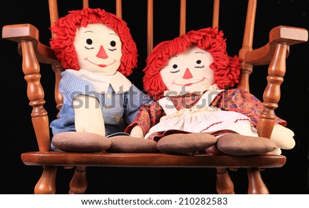 Rag doll is the most ancient children\'s toy in existence.  This is boy and girl dolls sitting in vintage maple rocking chair.