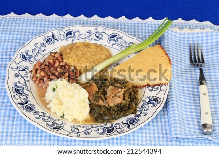 Country Cooking setting with blue plate of soul food on blue gingham background.  Collard greens and black-eyed peas with cornbread -- corn bread.