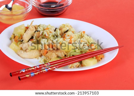Lemon Chicken stir fry dinner with pineapple chunks against red background with red chopsticks.