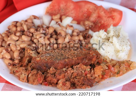 Soul food supper - meatloaf with black -eyed peas and mashed potatoes on red plaid tablecloth.  Closeup with selective focus.