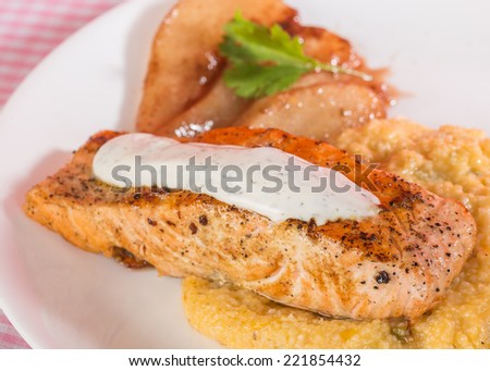 Wild-caught Salmon Steak on bed of cheese grits with pears candied in honey wine and cinnamon sugar sauce. Selective focus with shallow depth of field.