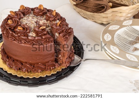Large slice on cake knife cut from beautiful German Chocolate Cake surrounded by dessert dishes.