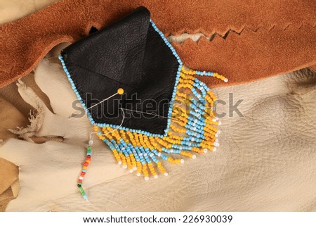 Black leather Native American beaded Medicine Bag against background of assorted animal skins.