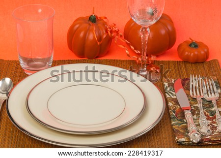 Fine China, silver and crystal on table with Autumn Colors and decorative pumpkin candles ready for the Holidays.
