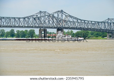 Tug boat pushing loaded barges beneath the Mississippi River Bridge between Natchez Mississippi and Louisiana.