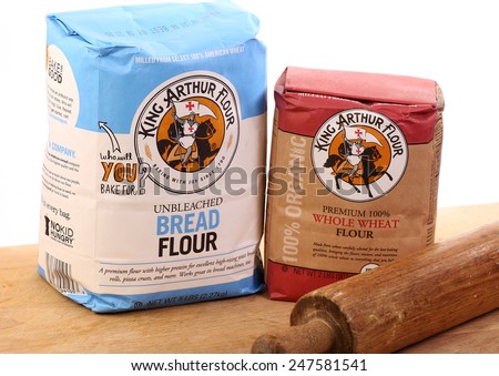 LLANO, TEXAS-JAN 27, 2015: Bag of King Arthur Unbleached Bread Flour and bag of Premium 100% Whole Wheat Flour on wooden cutting board with antique rolling pin. White background with copy space.