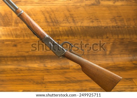 Reminiscent of Cowboys and Indians the vintage lever action rifle is a prop in most Cowboy Movies.  Shallow depth of field against rustic wood background.