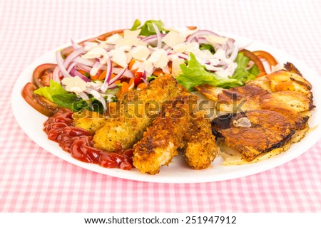 Bright light from upper right over deep fried chicken strips with golden brown onion and potato frittata.  White plate against pink gingham tablecloth with large chef salad.