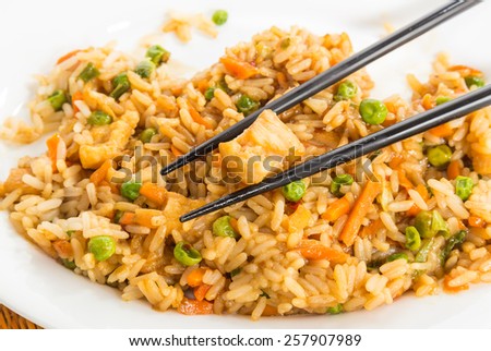 Plate of chicken fried rice with chopsticks on white plate