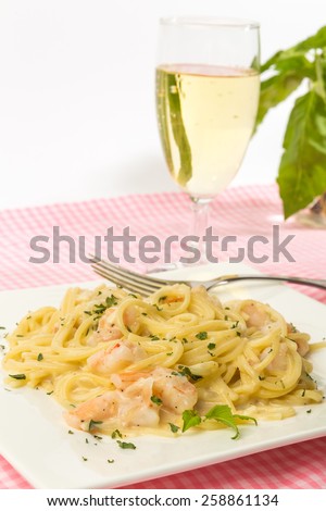 Shrimp Alfredo Dinner with glass of fruity Riesling white wine against white background with copy space.  Vertical format.