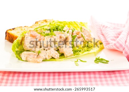 Spicy seasoning on shrimp salad in lettuce leaf wrap with slice of jalapeno cheese loaf on bright white background;  Pink gingham napkin and place mat.  Strong light from right rear.