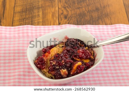 Blackberry Cobbler Dessert in white bowl on pink gingham tablecloth on rustic wooden picnic table.  Southern Cooking with copy space.