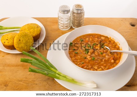 Bowl bean soup with dried great northern beans and jalapeno cornbread muffins and fresh green scallions.