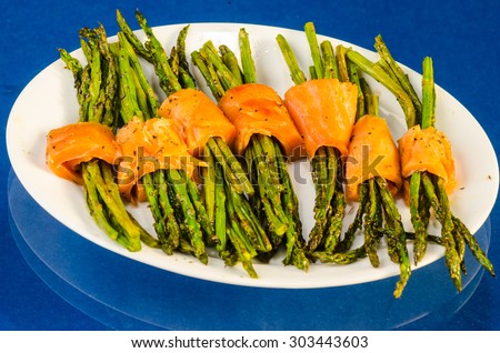 Smoked Salmon and Asparagus Hors-d\'oeuvres on white platter against blue reflective background.  Top Down View.
