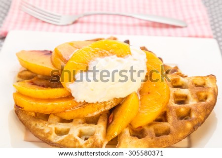 Sliced peaches on hot waffles topped with whipped cream.