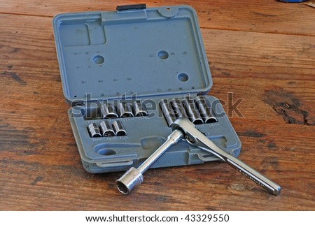 Small socket wrench set isolated on old scratched and scarred wooden-top workbench.