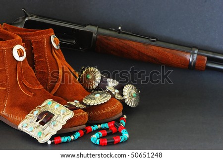Montage of native american turquoise and silver jewelry, moccasins, and winchester rifle on dark background