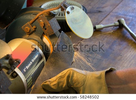 Tight shot of man\'s hand holding lawnmower blade against old, rusty 6\