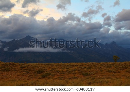 Low hanging clouds shroud Teton Mountains at sunset after summer storm dropped snow and rain in upper levels of Grand Teton National Park, Wyoming.