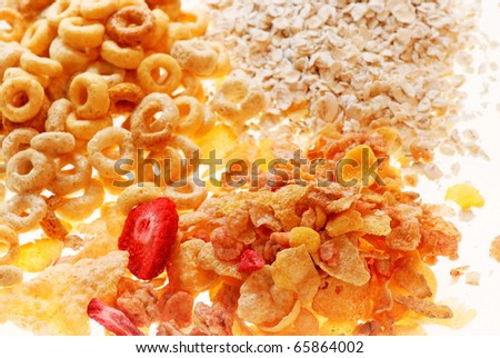 Light shining through three different dry breakfast cereals; oatmeal, toasted oats, and mixture of wheat, corn and barley with strawberries.
