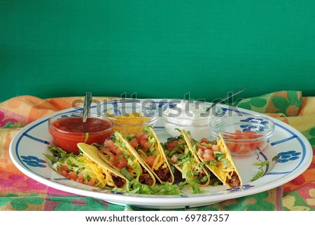 Crispy tacos in shells with bowls of ingredients on a colorful background.