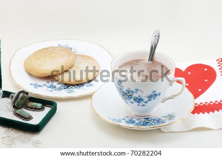 Hot Chocolate and cookies on elegant china in a Valentine setting with gift of turquoise jewelry and valentine napkin.