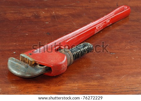 Large 16-inch pipe wrench laying on wooden workbench.  Sometimes called a Monkey Wrench.