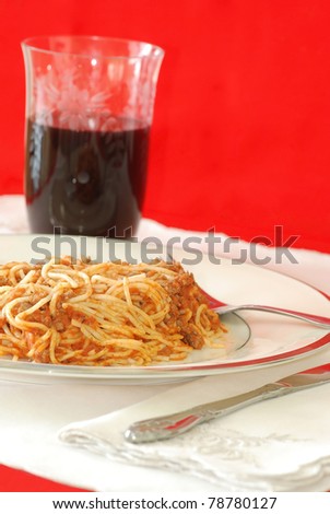 Spaghetti on fine china plate with expensive linen napkins and beautiful crystal glass filled with red wine.
