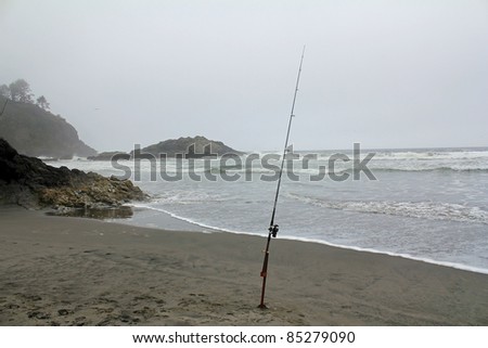 Fisherman\'s rod and reel stuck in sand of Pacific beach on foggy, misty day along coast of Washington