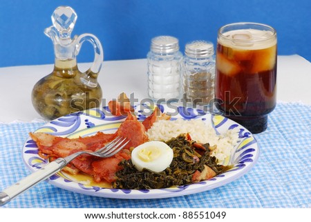 Plate of pure southern cooking with typical country-kitchen look.  Turnip greens and salt pork on old fashioned plate with antique pepper sauce container.