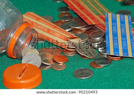 Assortment of coins poured from homemade bank to be sorted and rolled in paper rollers.