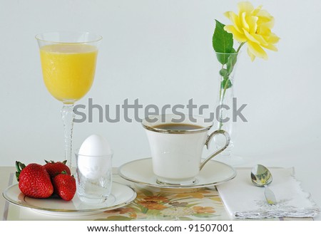 Continental Breakfast of egg, fruit, coffee and juice on fine china and elegant stem-glass crystal in cheerful setting.