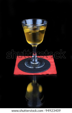 Yellow cocktail on red napkin reflecting in glossy black finish of bar.