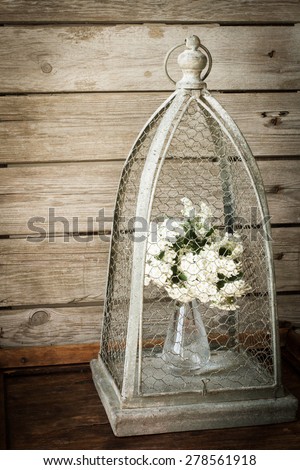 flowers in a vase in a cage for birds. on a wooden background