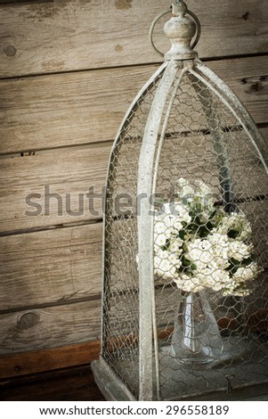 flowers in a vase in a cage for birds. on a wooden background