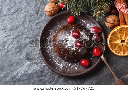 Christmas chocolate pudding with cranberries, walnuts, cinnamon, apples and oranges. Dark background
