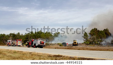 ORANGE COUNTY, FL - JANUARY 8: Orange County and Florida Forestry Service fire fighters and their equipment stand by a controlled brush / forest fire on January 8, 2010 in Orange County, FL.