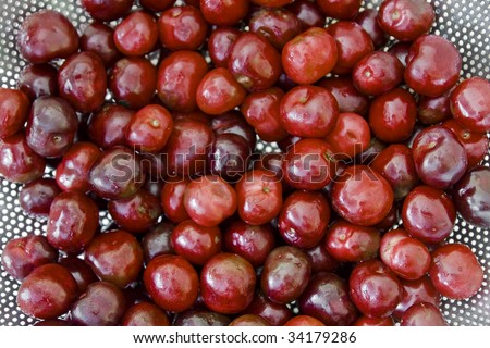 Fresh deep red cherries in a colander with stalks removed