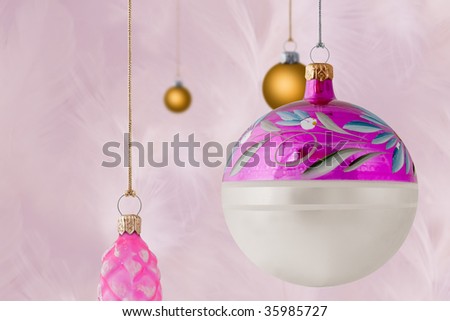 Pink and gold glass christmas baubles on soft pink feather background