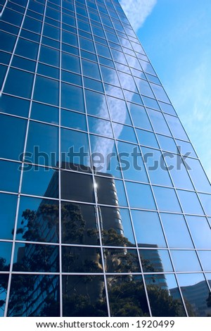 Contrails from an airplane reflecting on the glass of an office building