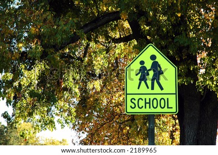 A school crossing sign set against autumn trees