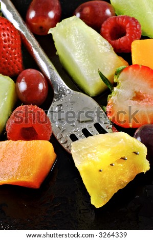 Variety of fresh fruit prepared for a salad on a watery black plate