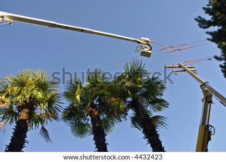 A boom crane lifts and secures power lines during installation of a new power pole