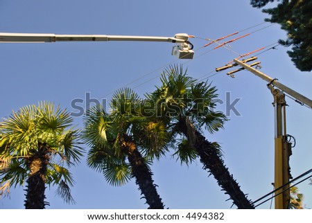 A boom crane lifts and secures power lines during installation of a new power pole