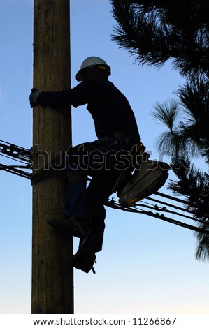 Silhouette of an electrician climbing a newly installed utility pole