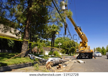 Utility truck lifts a severed power pole and lines after an accident