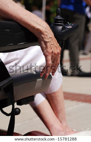Hand of an elderly woman draped over the arm of her electric scooter